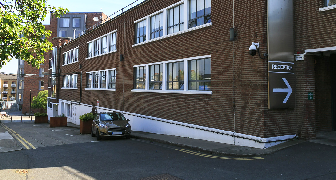 The brick exterior of the Digital Depot building at The Digital Hub. A sign points the way to the reception.